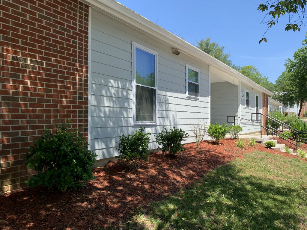 a side view of a white house with a brick wall