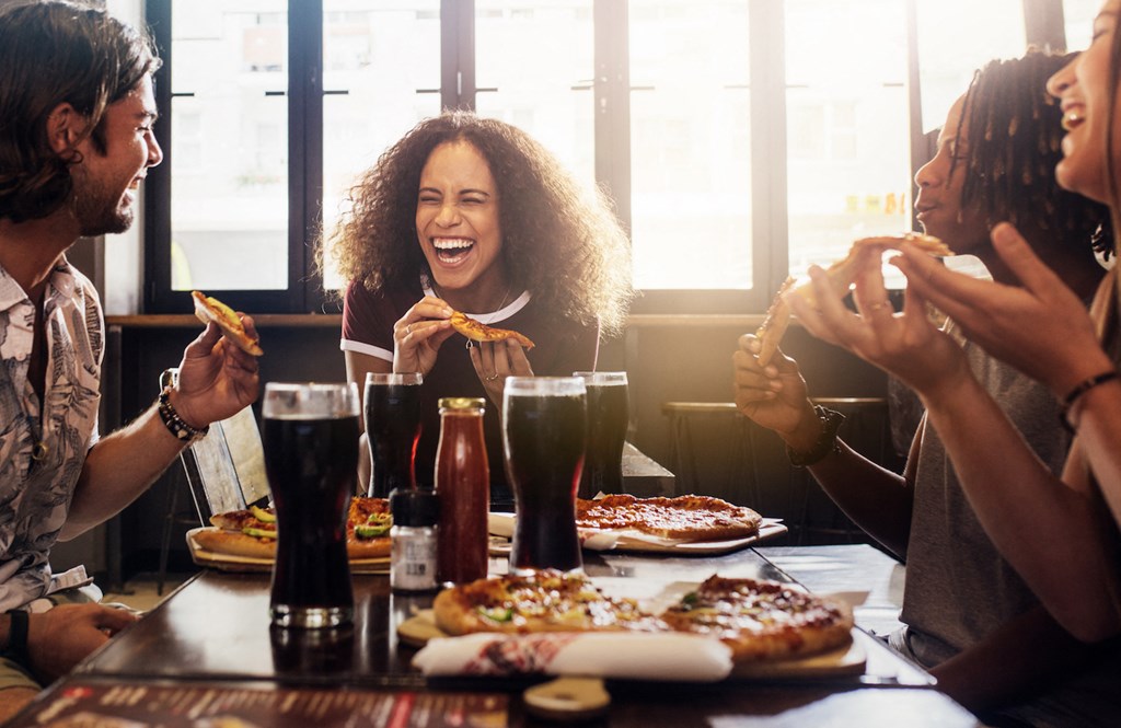 group of young people eating pizza at a restaurant
