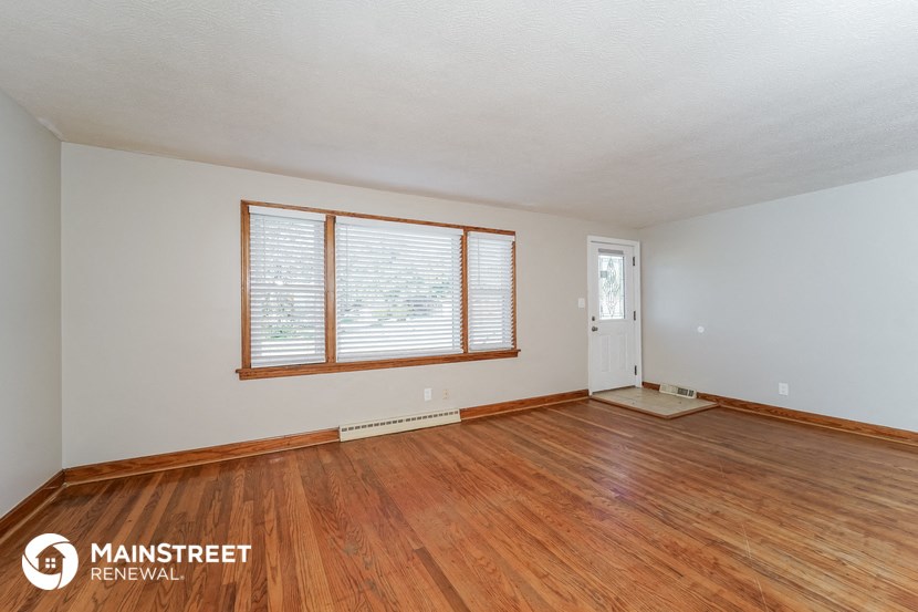 the living room of a home with wood flooring and a door and window