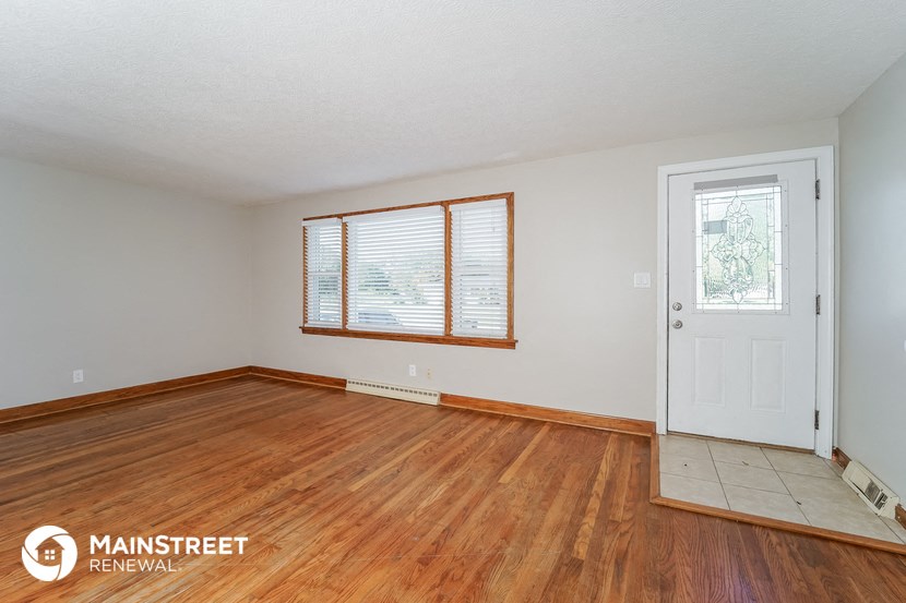 the living room of a house with wood floors and a white door