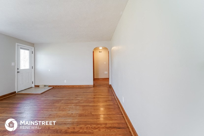 the living room and dining room with wood flooring and white walls