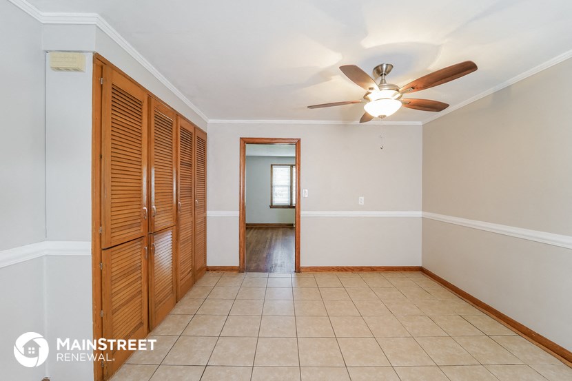 an empty living room with a ceiling fan and wooden closet