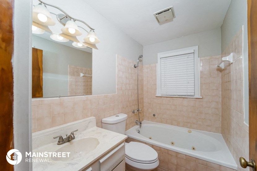 a bathroom with a tub sink and toilet and a mirror
