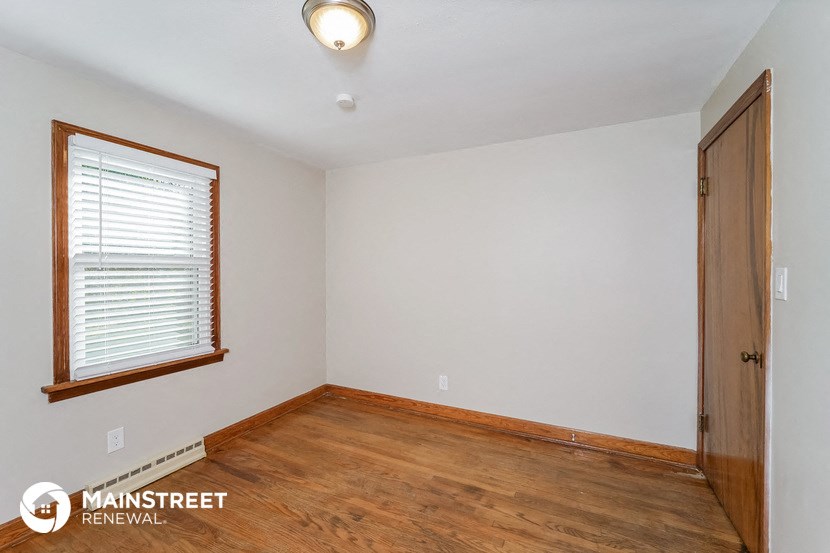 the living room of an empty house with wood flooring and a window