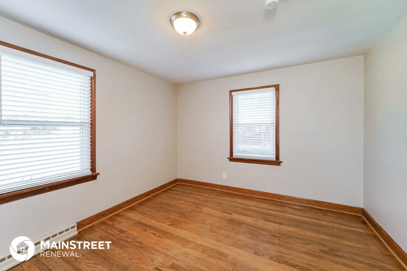 the living room of a home with wood flooring and two windows