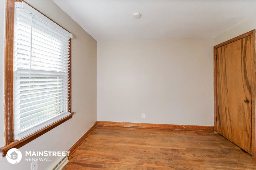 a bedroom with wood flooring and a large window and a wooden door