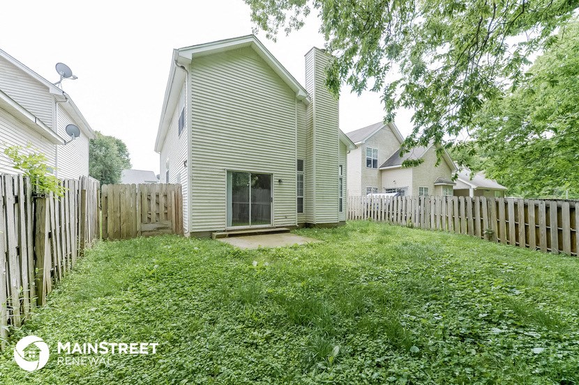a backyard with a white house and a wooden fence