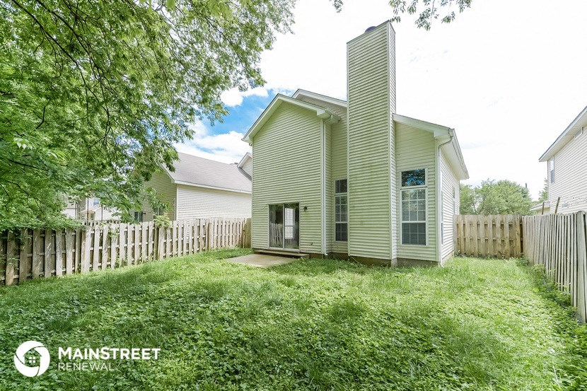 the back of a house with a yard and a white fence