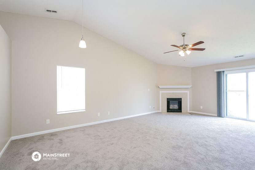 the spacious living room with fireplace and ceiling fan