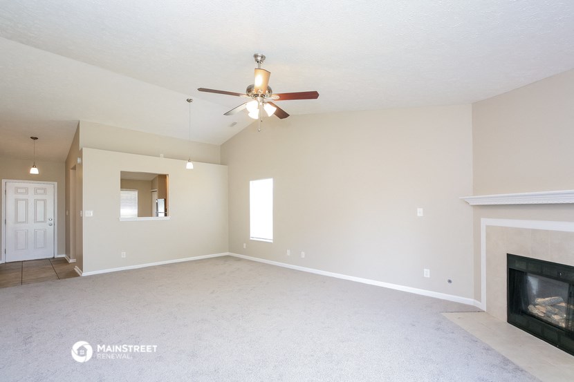 the spacious living room with fireplace and ceiling fan