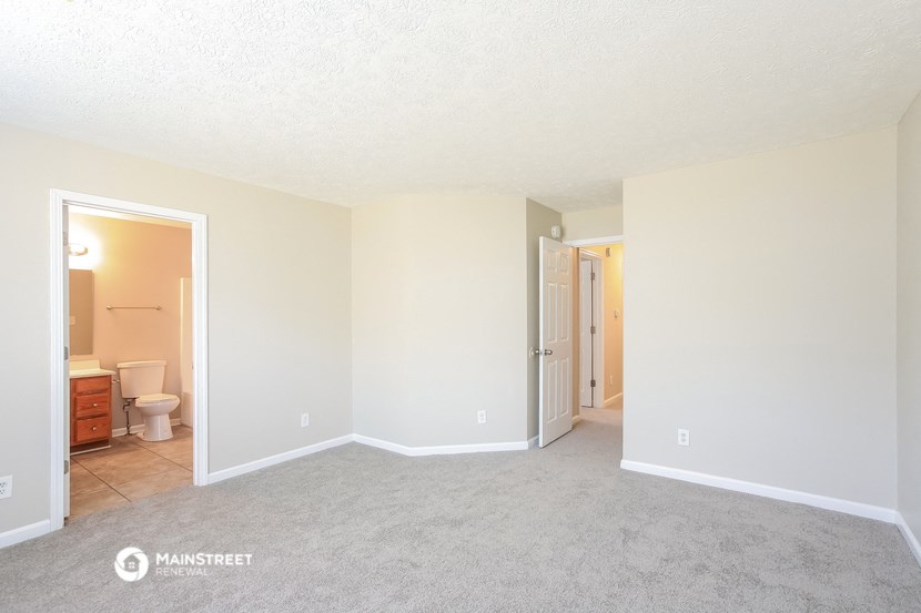 an empty living room with a door into a bathroom