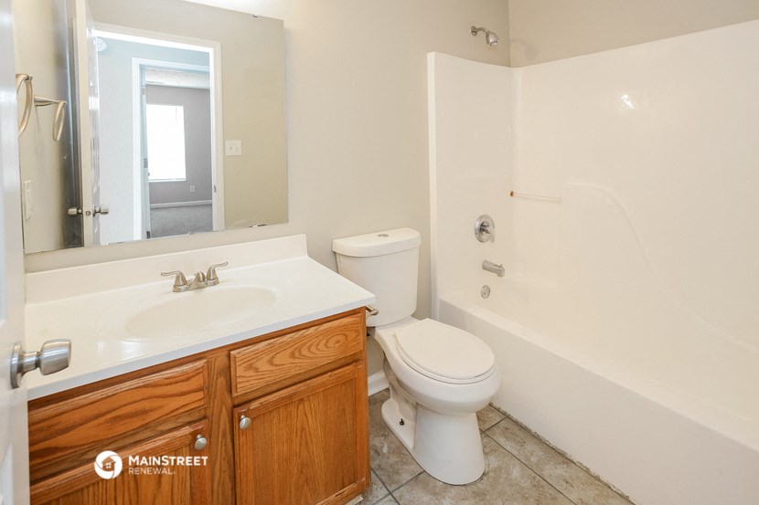 a bathroom with a toilet sink and tub and a mirror