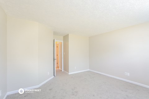 a spacious living room with carpet and white walls