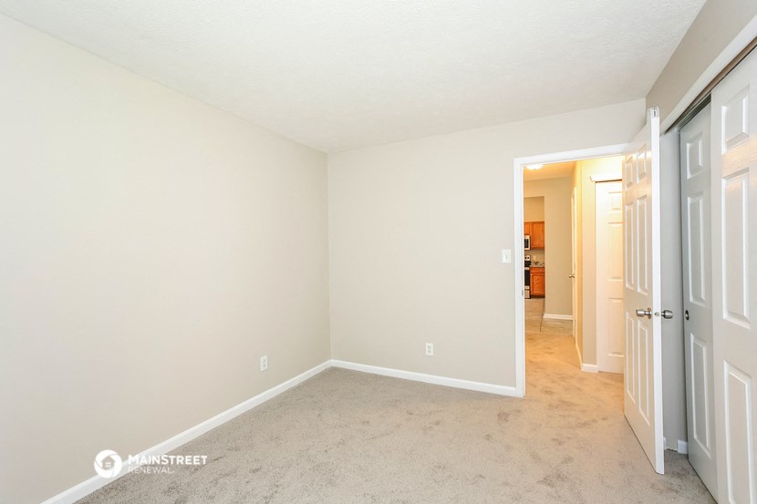 a bedroom with a carpeted floor and a door to a hallway