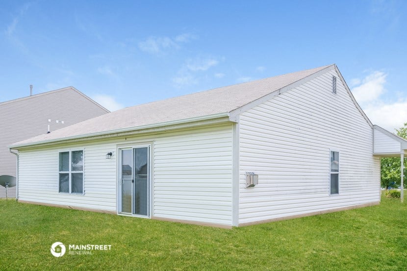 a small white house with white siding and a grass field