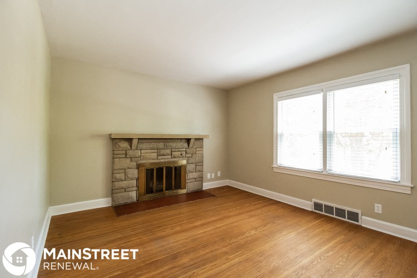 a living room with a stone fireplace and wooden floors