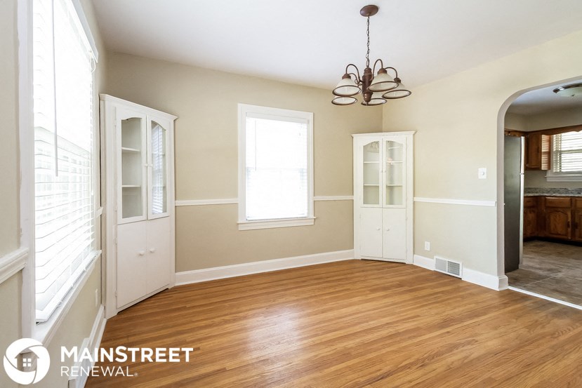 an empty dining room with a wood floor and a chandelier