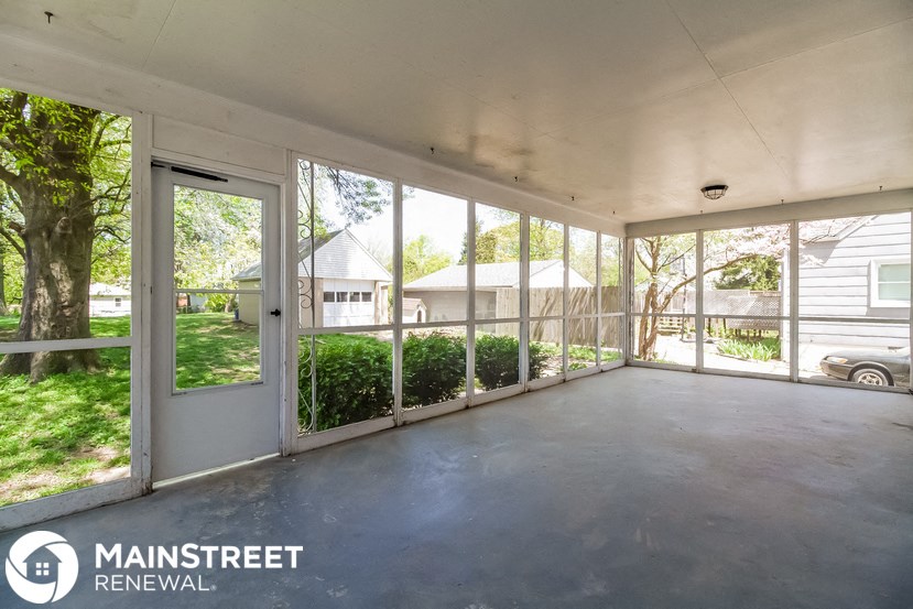 the screened in porch of a home with large windows
