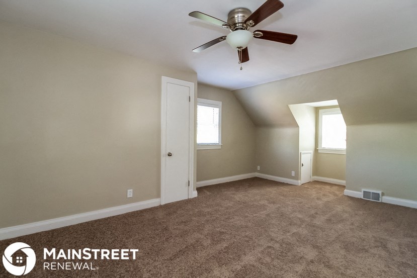 an empty living room with carpet and a ceiling fan