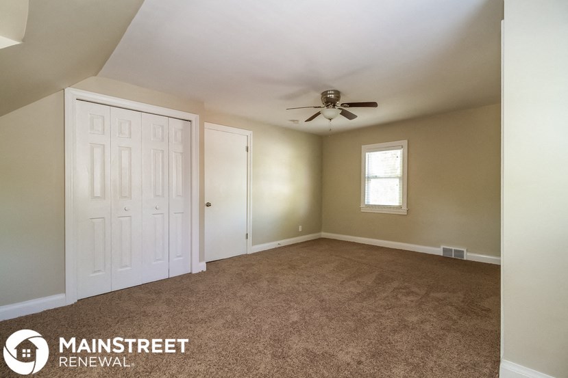 an empty living room with a ceiling fan and a closet