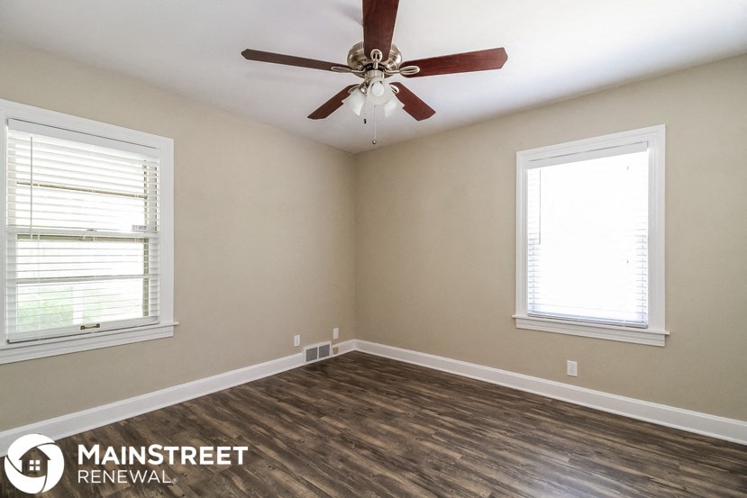 a living room with a ceiling fan and two windows