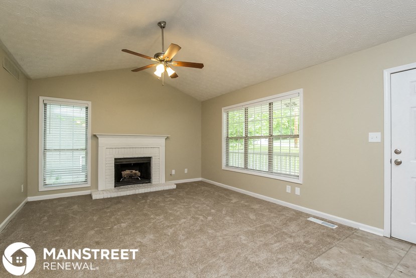 a living room with a fireplace and a ceiling fan