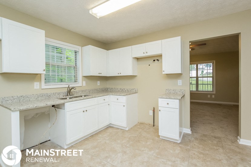 a kitchen with white cabinets and granite counter tops and a sink