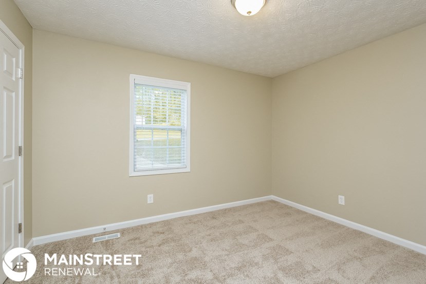 a bedroom with a carpeted floor and a window