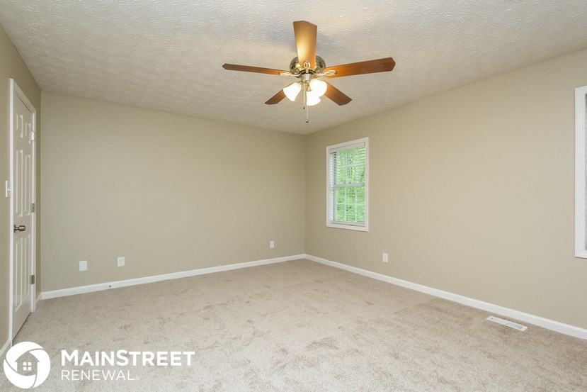 a bedroom with a ceiling fan and a carpeted floor