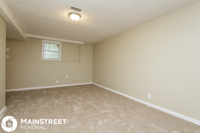 the spacious living room in this manufactured home has carpeted floors and beige walls