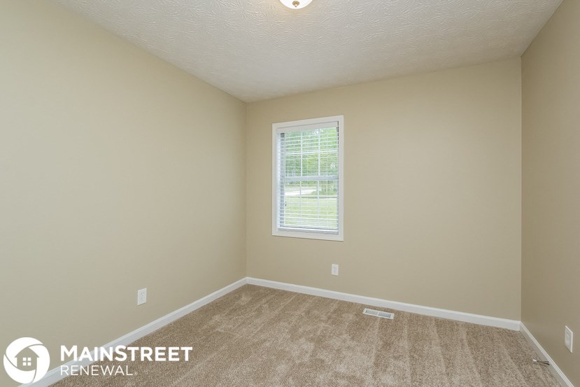 the upstairs bedroom has a carpeted floor and a window