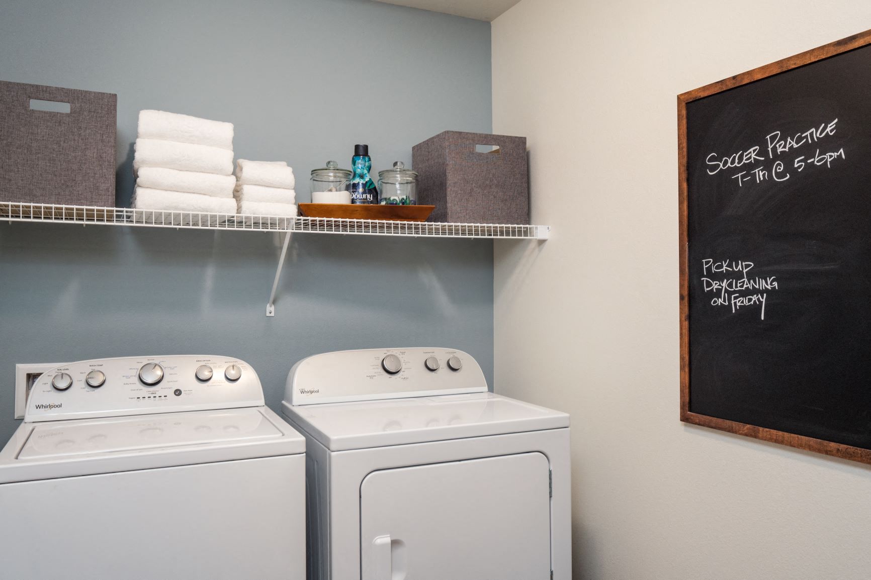a washer and dryer in a laundry room with a chalkboard and towels