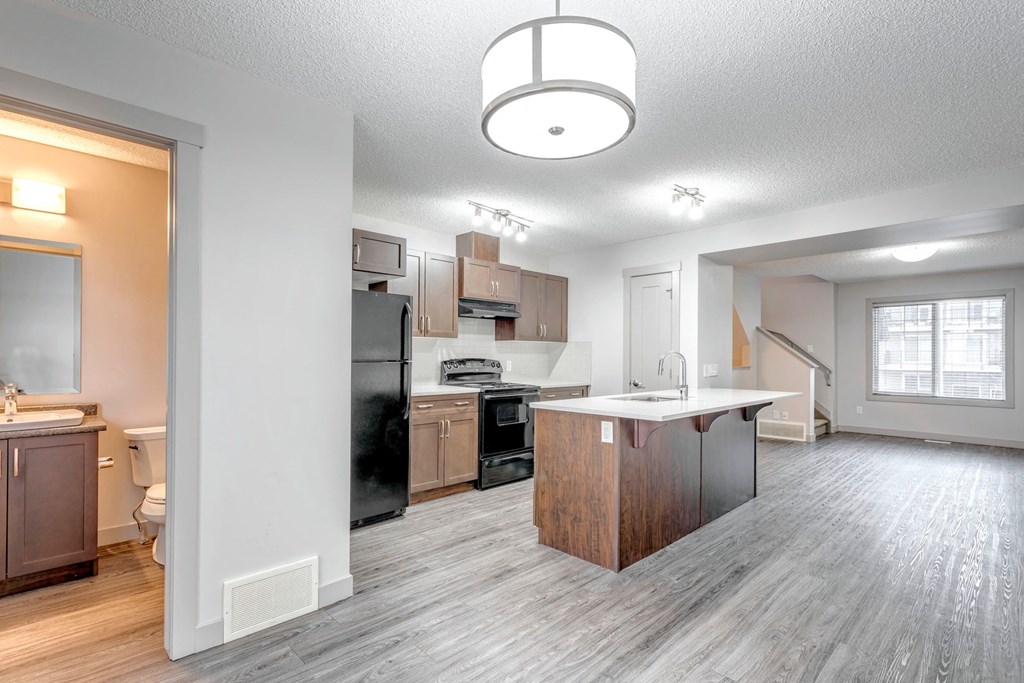 A modern kitchen with a black refrigerator and wooden island.
