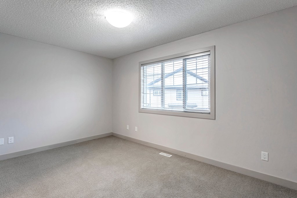 A room with a window and a carpeted floor.