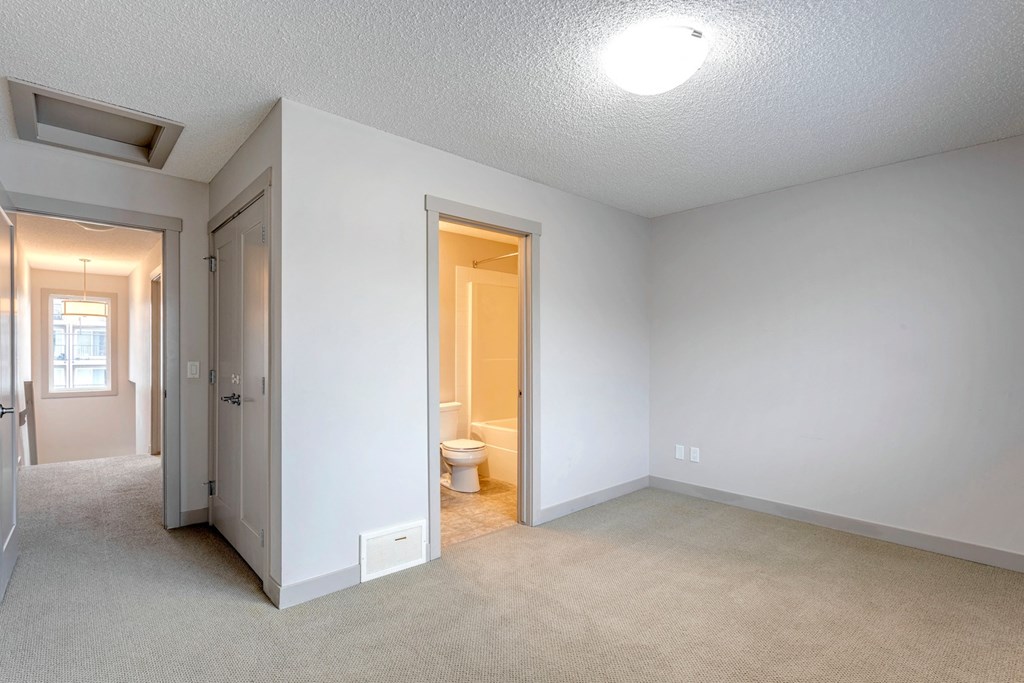 A room with a toilet and a doorway leading to another room.
