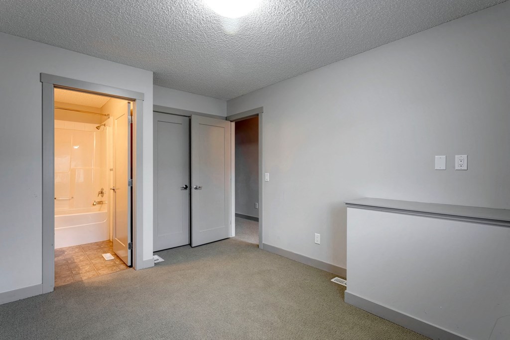 A white room with a carpet floor and a window.