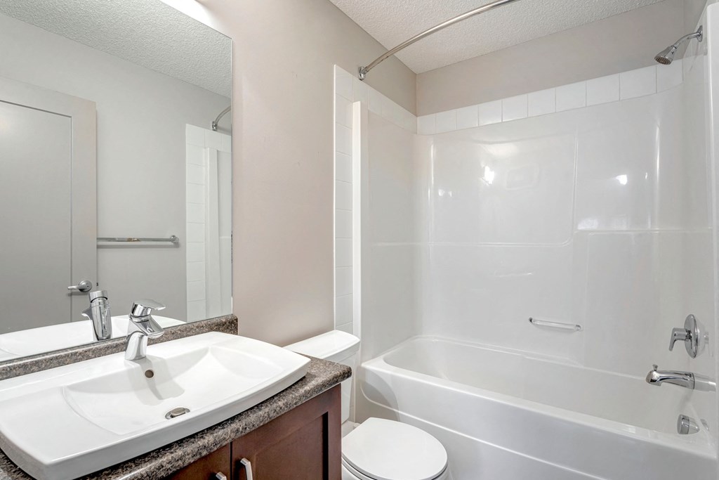 A white sink is on a brown countertop in a bathroom.