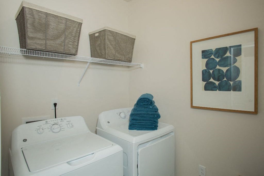 a white washer and dryer in a room with a painting and a shelf