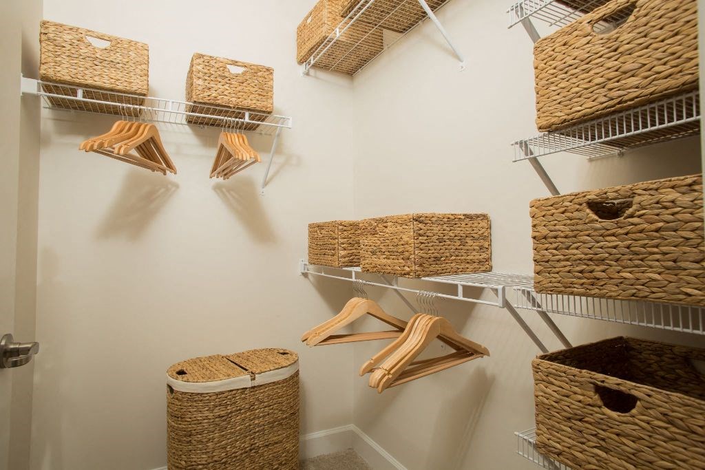 a walk in closet with baskets and racks