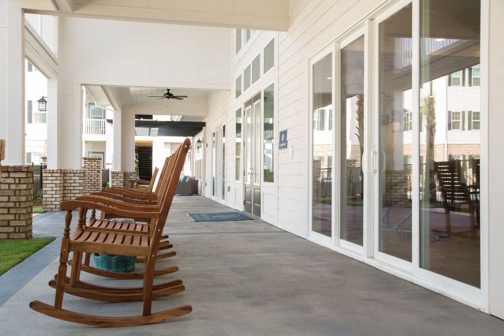 a row of wooden rocking chairs on a porch