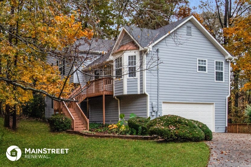a blue house with a wood deck and a tree