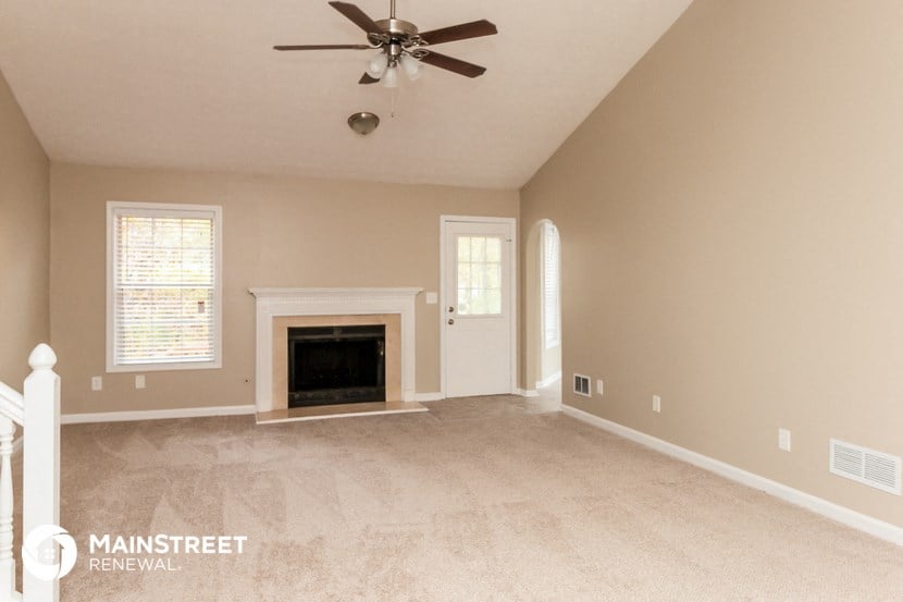 a living room with a fireplace and a ceiling fan