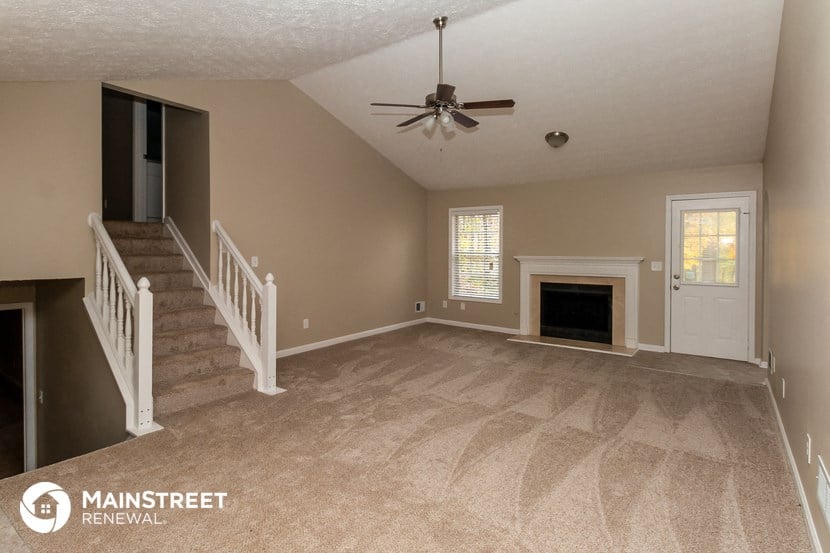 an empty living room with a fireplace and a ceiling fan