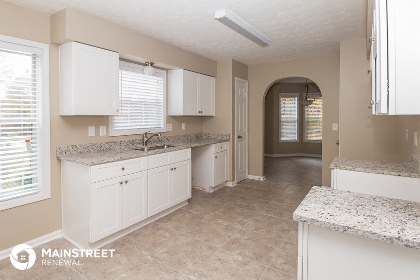 a large kitchen with white cabinets and granite counter tops