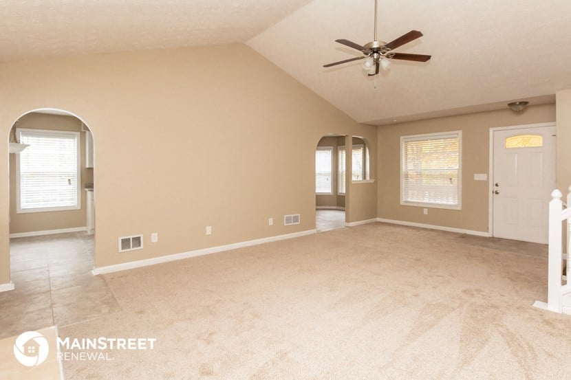an empty living room with a ceiling fan