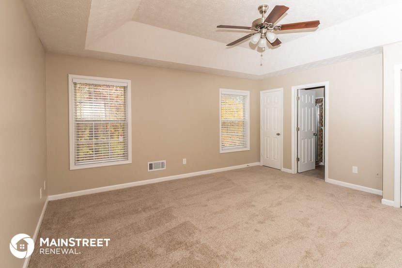 the spacious living room with carpeting and a ceiling fan