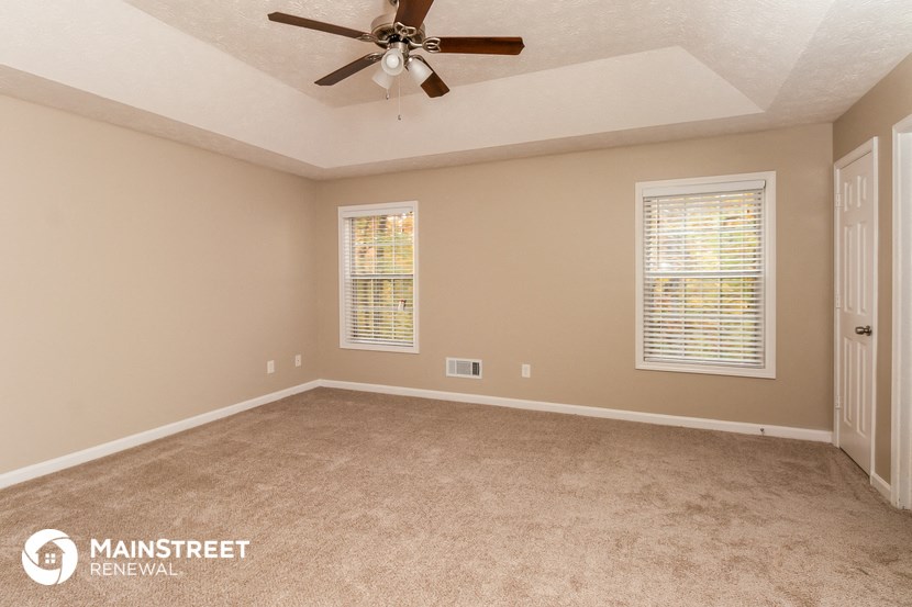 the master bedroom has a carpeted floor and a ceiling fan