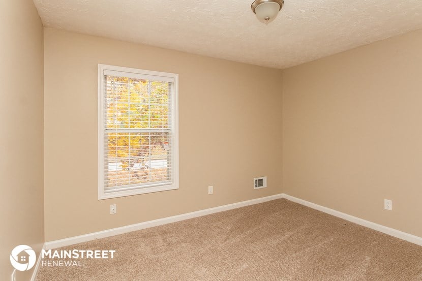 the upstairs bedroom has a large window and carpeted flooring