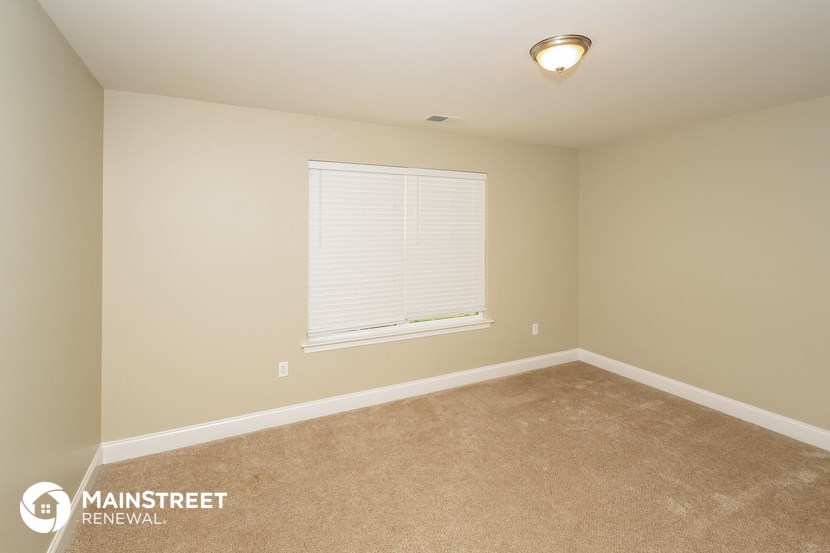 the upstairs bedroom has a large window and carpeted flooring