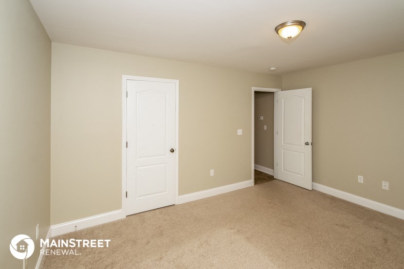 a bedroom with two doors and a carpeted floor and a door to a closet
